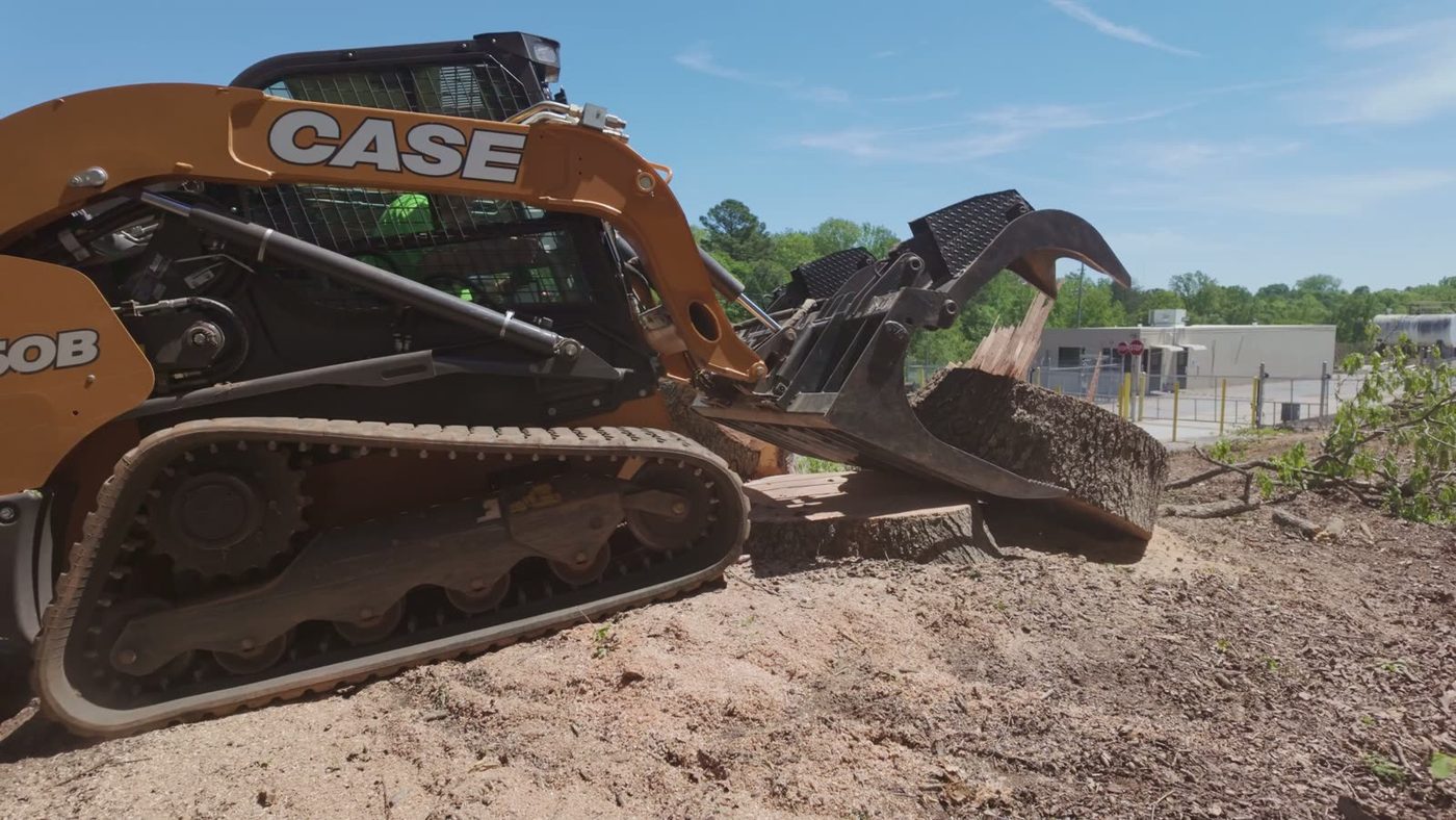 Tracked grapple loader clearing debris
